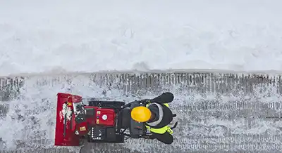 Overhead view of man pushing snow thrower.