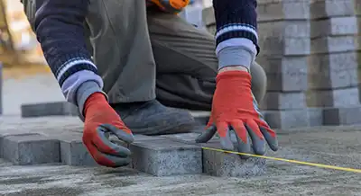 Closeup of worker installing brick pavers.